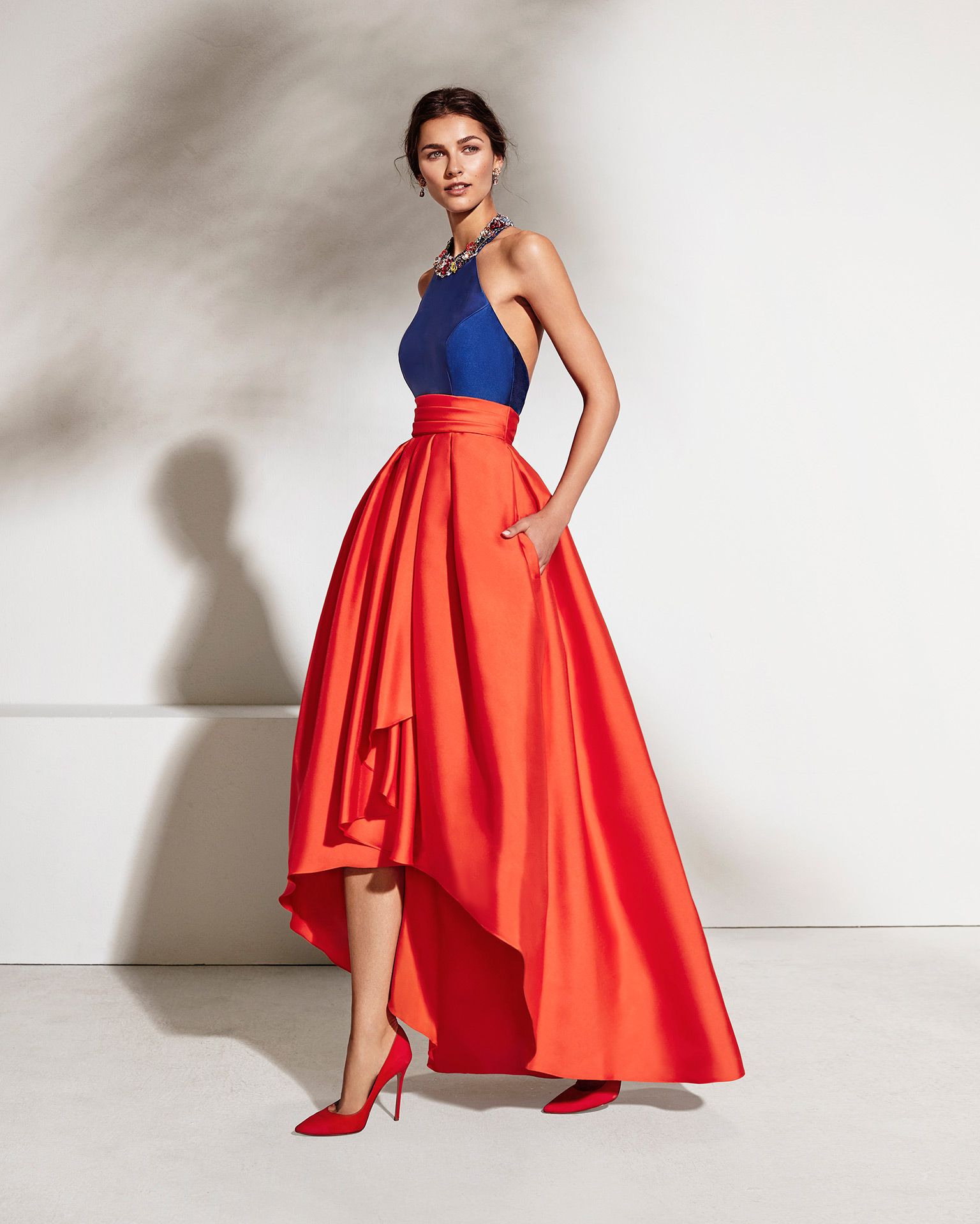 Long mikado cocktail dress with open back and beaded neckline. Available in cobalt/coral and coral/cobalt. 2018 MARFIL BARCELONA Collection.