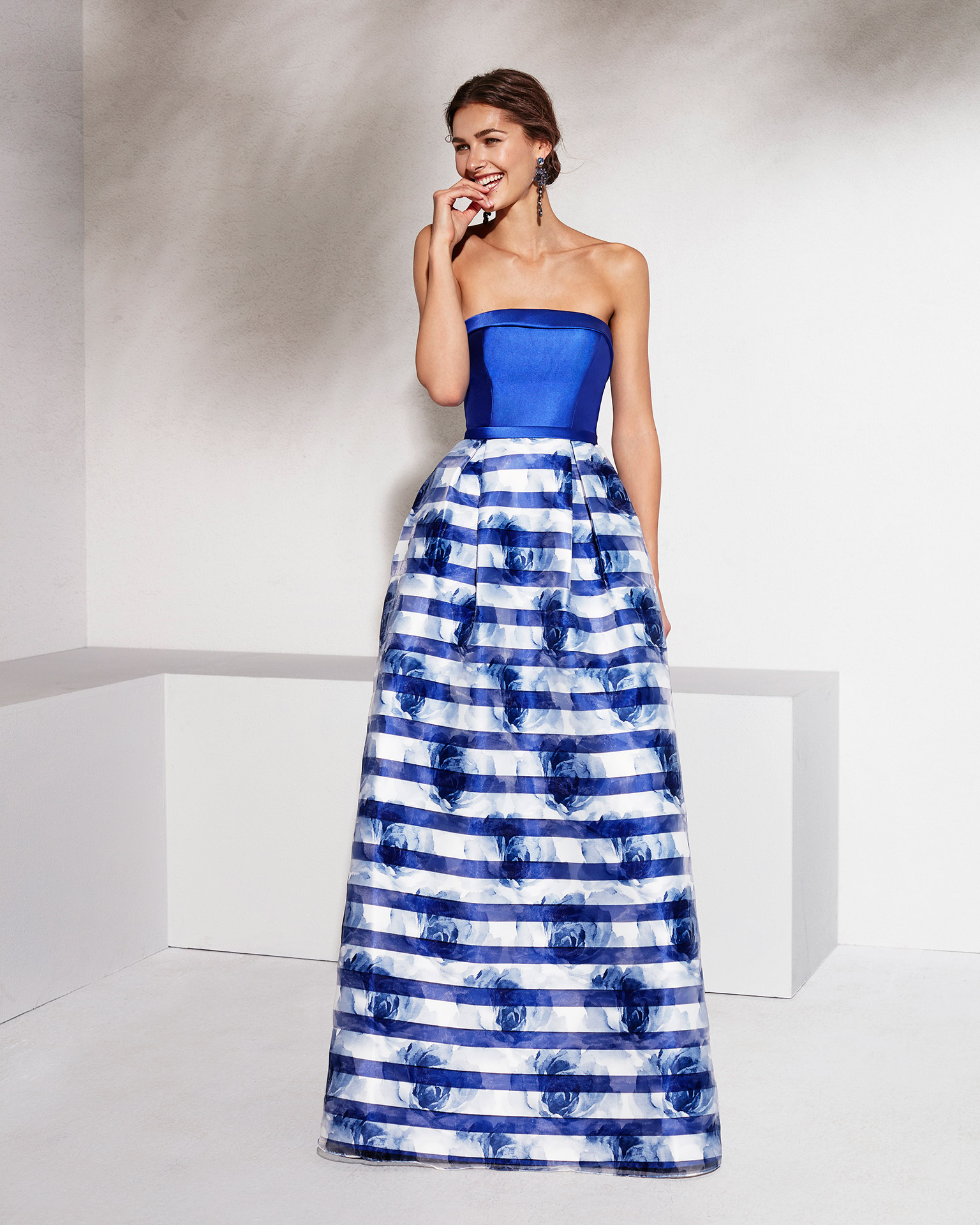 Long organza and mikado cocktail dress with strapless neckline. Available in black/coral print, cobalt/cobalt print and silver/silver print. 2018 MARFIL BARCELONA Collection.