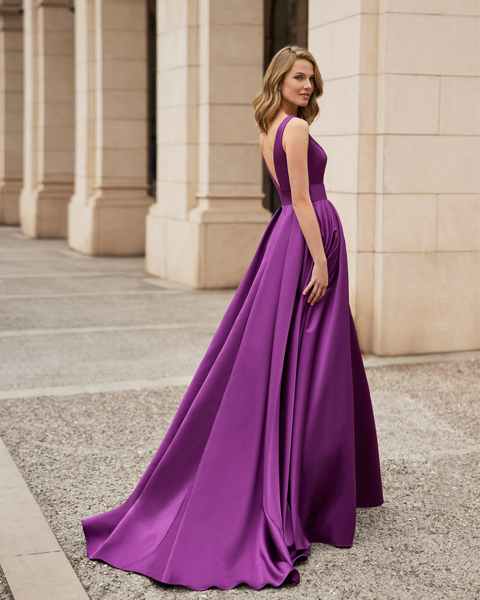 Long evening dress made of satin. Marfil Barcelona design with a V-neckline, and a pleated skirt with a slit. MARFIL_BARCELONA.
