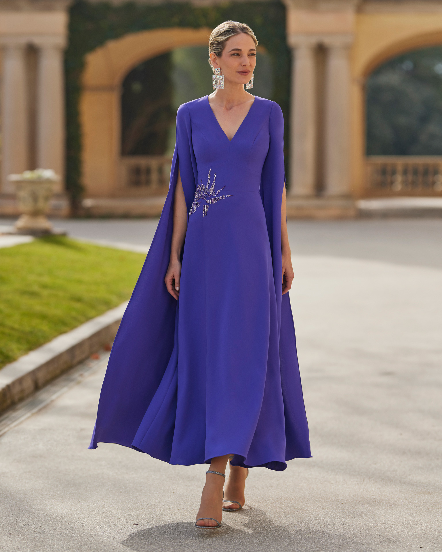 Simple long mother of the bride or groom dress. Crafted in triacetate with beadwork details. With V-neckline, closed back and cape sleeves. Couture Club design. MARFIL_BARCELONA.