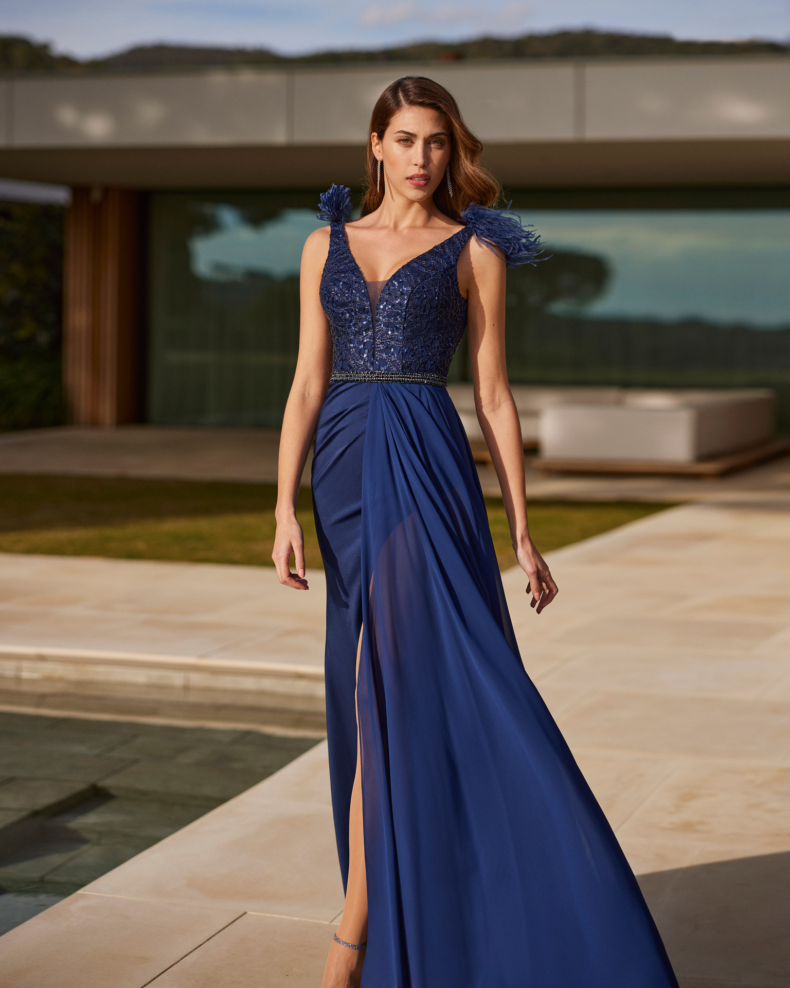 Fairytale style long evening dress. Crafted in crespon and beadwork. With a V-neckline and back with feathered straps. Marfil Barcelona design for parties and celebrations. MARFIL_BARCELONA.