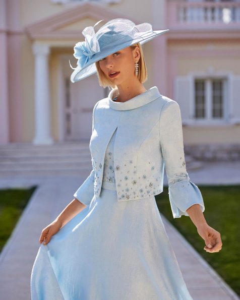 Abito da cerimonia corto composto da due pezzi confezionato in broccato con applicazioni di strass. Completano l'abito lo scollo girocollo, la schiena con chiusura a zip, le maniche corte e il soprabito con applicazioni di strass. Modello Couture Club. MARFIL_BARCELONA.