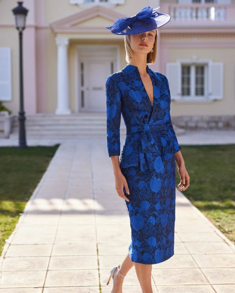 Vestido de fiesta corto. Confeccionado en brocado. Con escote pico, espalda cremallera y manga francesa. Falda con abertura trasera y lazo irregular. Conjunto Couture Club. MARFIL_BARCELONA.