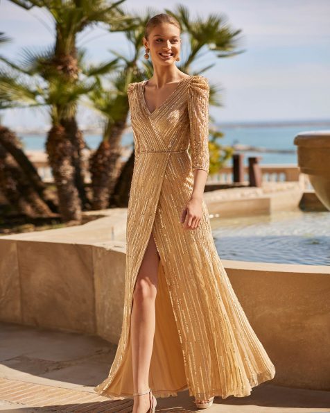 Abito da cerimonia lungo realizzato con paillettes. Con corpetto con scollo a V, apertura sulla schiena e maniche francesi. Modello Couture Club. MARFIL_BARCELONA.
