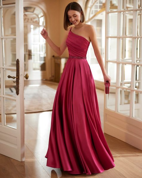 Modern long guest dress, crafted in satin embellished with beadwork. An asymmetric neckline and a shawl complete the design. A Marfil Barcelona design. MARFIL_BARCELONA.