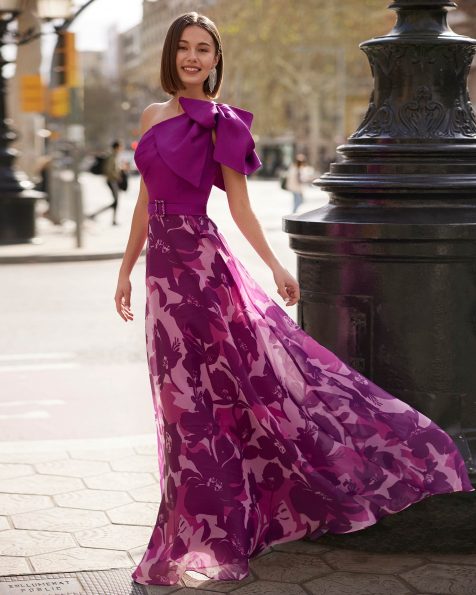 Youthful long guest dress crafted in organza. An asymmetric neckline and a shawl complete the design. A Marfil Barcelona look. MARFIL_BARCELONA.