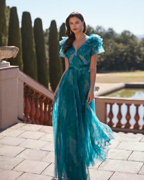 Abito da cerimonia lungo confezionato in tulle stampato. Con corpetto senza maniche con scollo a V sul davanti e sulla schiena e fiore decorativo. Un look Marfil Barcelona. MARFIL_BARCELONA.