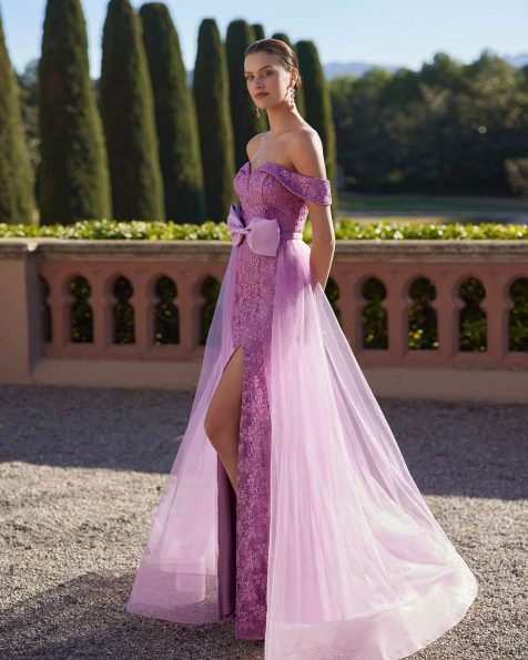 Two-piece long evening dress, crafted in lace, beadwork and tulle. Showcase a sweetheart neckline, open back, sleeveless bodice and skirt with a side slit. The asymmetric bow and overskirt complete the look. A Marfil Barcelona look. MARFIL_BARCELONA.