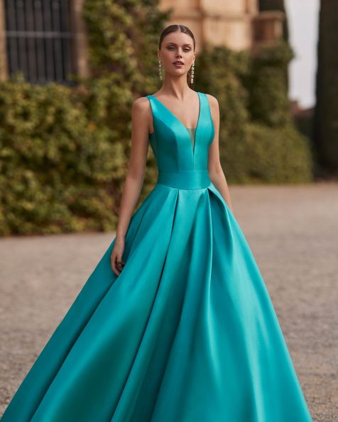 Long evening dress crafted in mikado. Featuring a V-neckline, open back, straps and a skirt with pockets. A Marfil Barcelona look. MARFIL_BARCELONA.