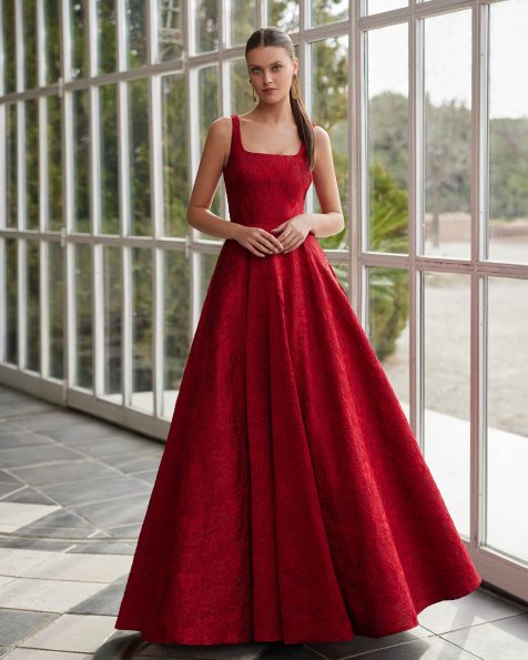 Long evening dress crafted in brocade. Featuring a square neckline, open back, straps and a flower embellishment. A Marfil Barcelona look. MARFIL_BARCELONA.