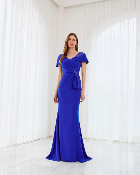 Vestido de fiesta largo, confeccionado en crepé y pedrería. Con escote pico, manga capa y chal. MARFIL_BARCELONA.