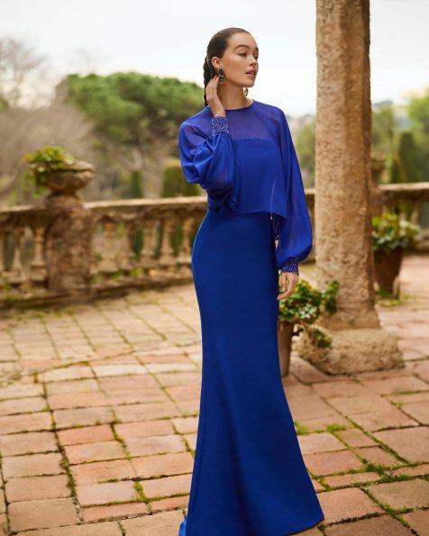 Abito da sera lungo due pezzi. Realizzato in crêpe elasticizzato. Scollo senza spalline e dettagli con perline. Include mantella. MARFIL_BARCELONA.