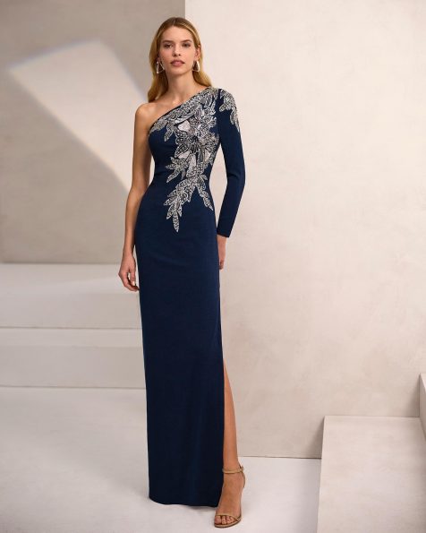 Vestido de fiesta largo. Confeccionado en crepé elástico. Escote asimétrico, manga larga y detalles con pedrería. Incluye chal. MARFIL_BARCELONA.