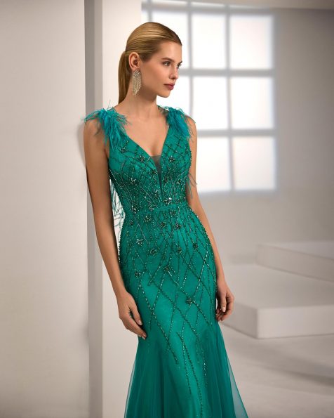 Vestido de fiesta largo. Confeccionado en pedrería. Escote pico, tirantes y espalda escotada. Detalles con plumas. Incluye chal. MARFIL_BARCELONA.