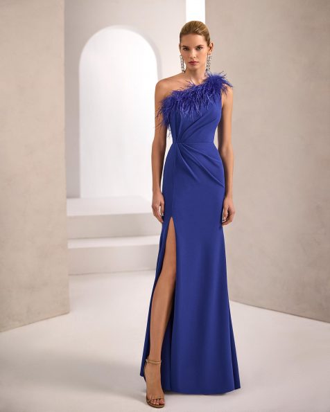 Vestido de fiesta largo. Confeccionado en crepé elástico. Escote asimétrico con plumas. Espalda cerrada. Incluye chal. MARFIL_BARCELONA.